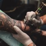 a man tattooing someone's arm